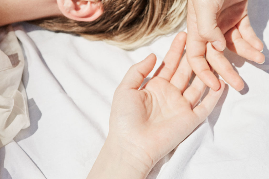 Ein Anschnitt einer jungen blonden Frau in der Sonne auf einem weißem Stoff.