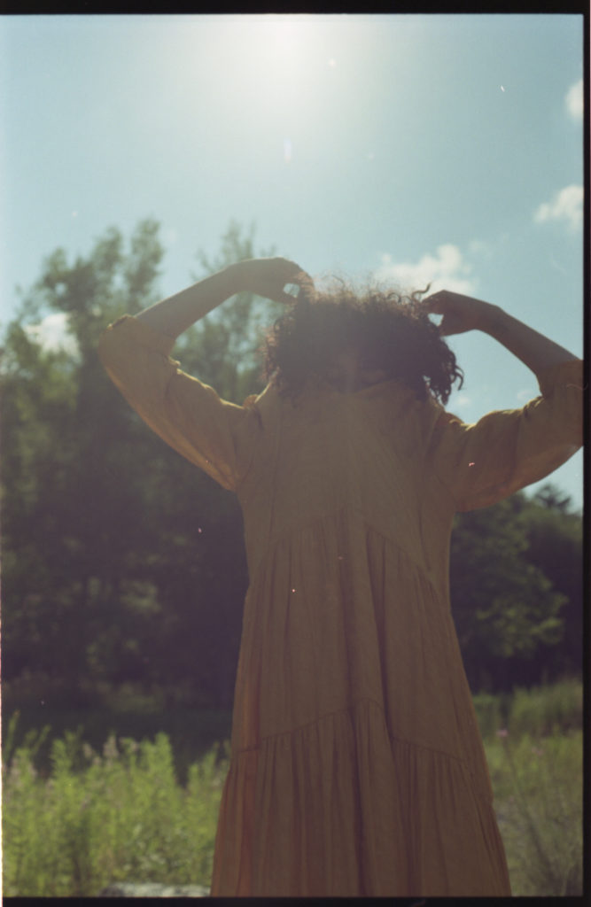 Junge Frau zieht sich das Kleid über den Kopf. Wirkt sehr lustig und zufällig. Aus dem Moment gerissene Fotografie.