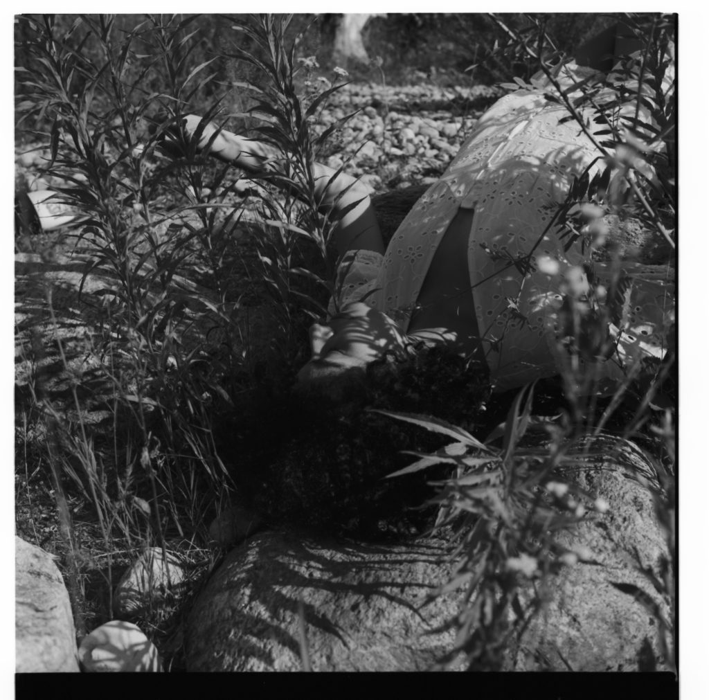 Junge Frau liegt in der Natur, in schwarz weiß fotografiert von Verena Voetter.