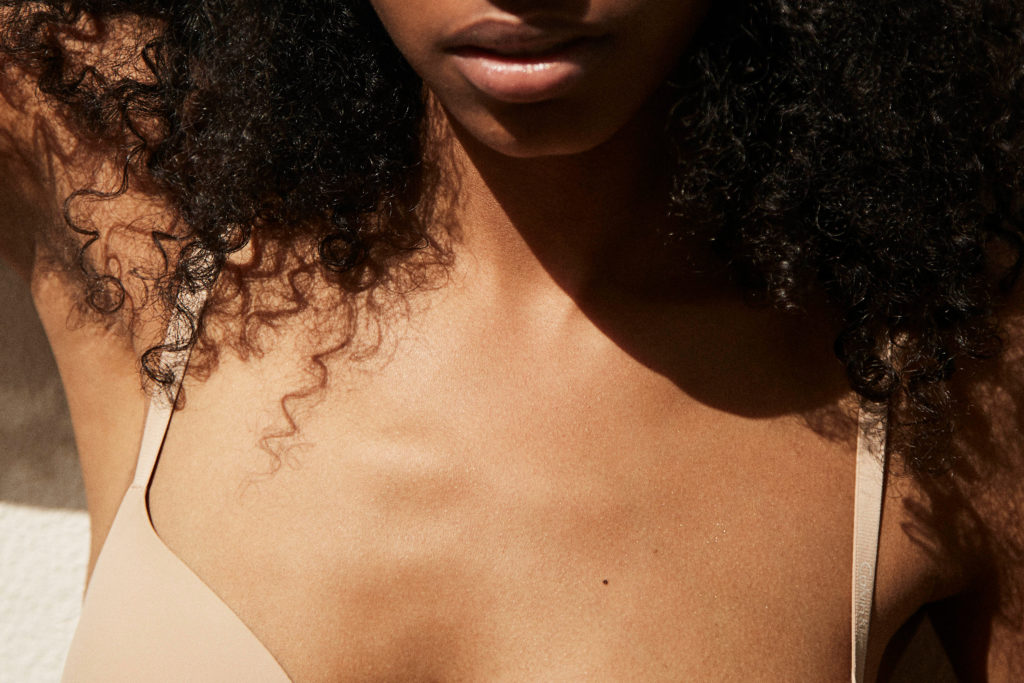 scharzes model im anschnitt, sehr viel haut zu sehen, sonnenlicht,