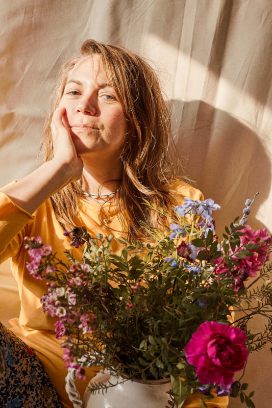 frau-mit-blumen-vor-leinwand-sonnenlich