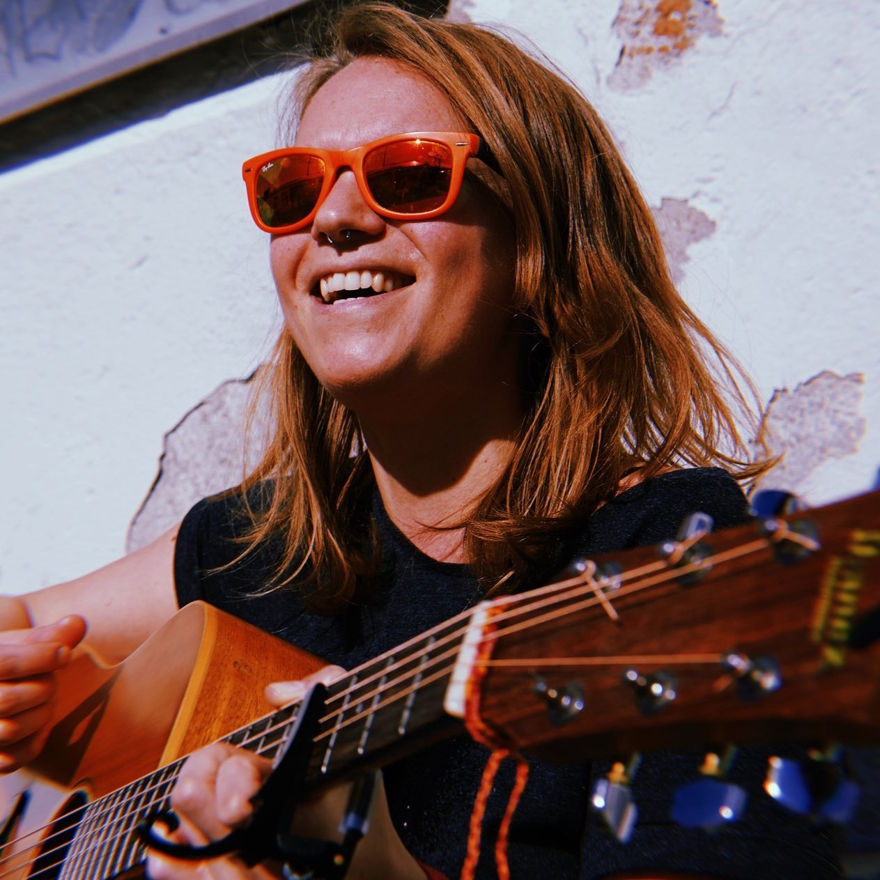 frau-singt-mit-gitarre-lacht-sonne-scheint