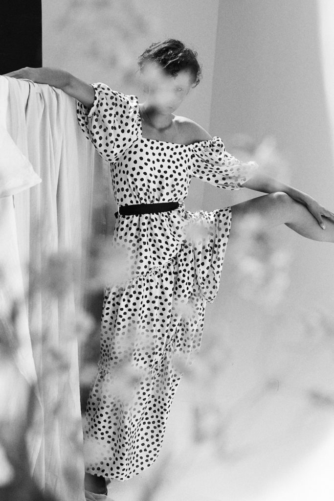 schwarz-weiß-foto-von-model-im-studio-stellt-bein-an-die-wand