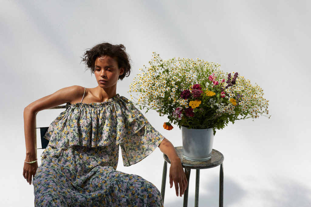 model-sitzt-mit-blumenstrauss-im-studio-im-halbschatten-sehr-sommerlich-natürlich
