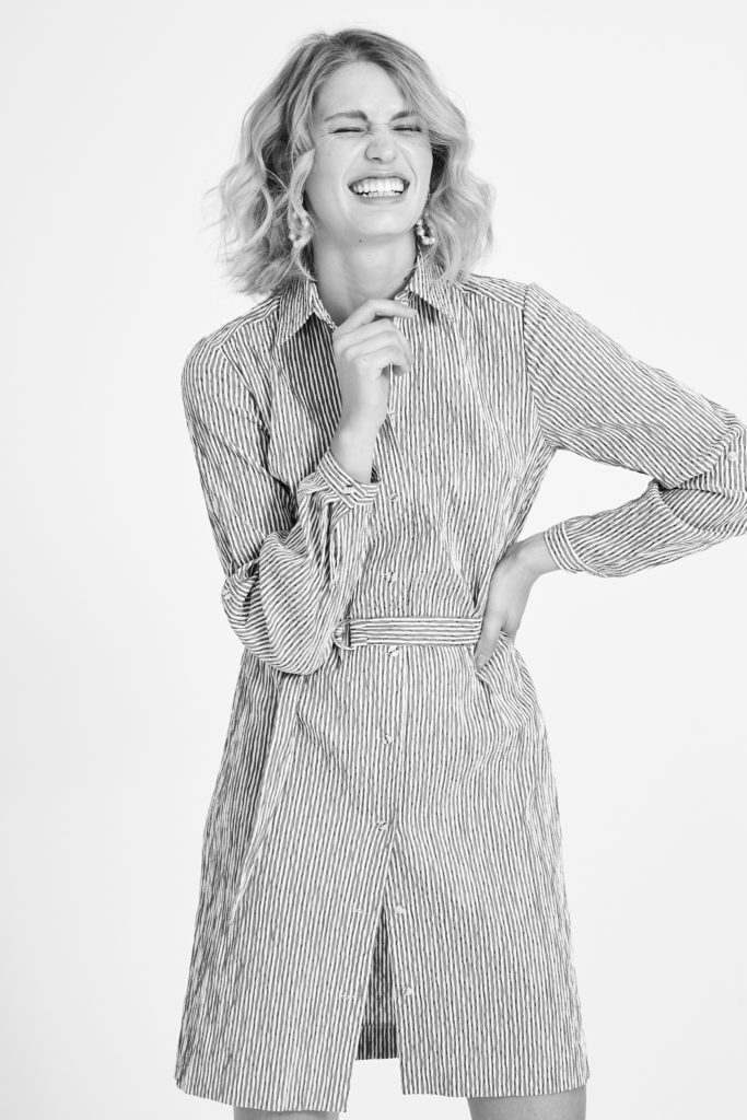 Schwarz weiß Foto von einem weiblichen Model im Studio, dass mit geschlossenen Augen lacht.