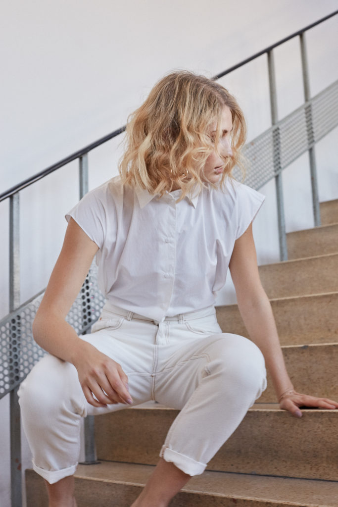 Junge Blonde Frau setzt sich gerade auf eine Treppe. Moderne Modefotografie.