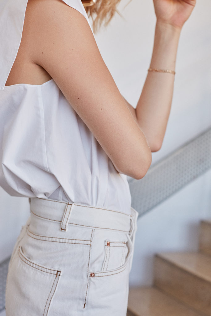 Nur der Oberkörper eines weiblichen Models in weißer Kleidung ist zu sehen. Sehr reduzierte Fotografie.