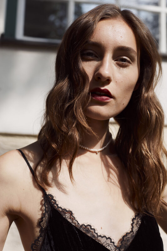 Modefoto von einem weiblichen Model in der direkten Sonne. Sehr elegant und modern.