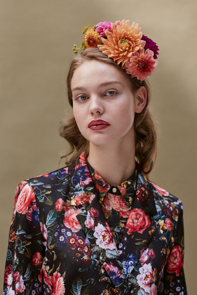 model-frontal-mit-blumen-in-den-haaren-schaut-streng