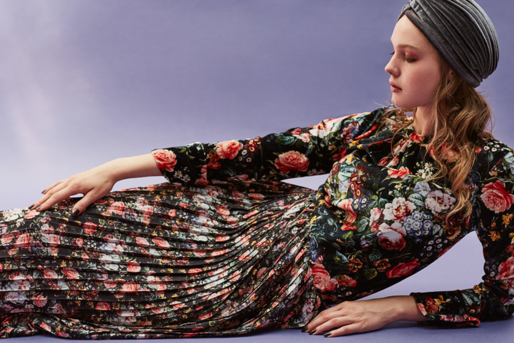 Weibliches Model liegt auf dem Boden im Blumenkleid.