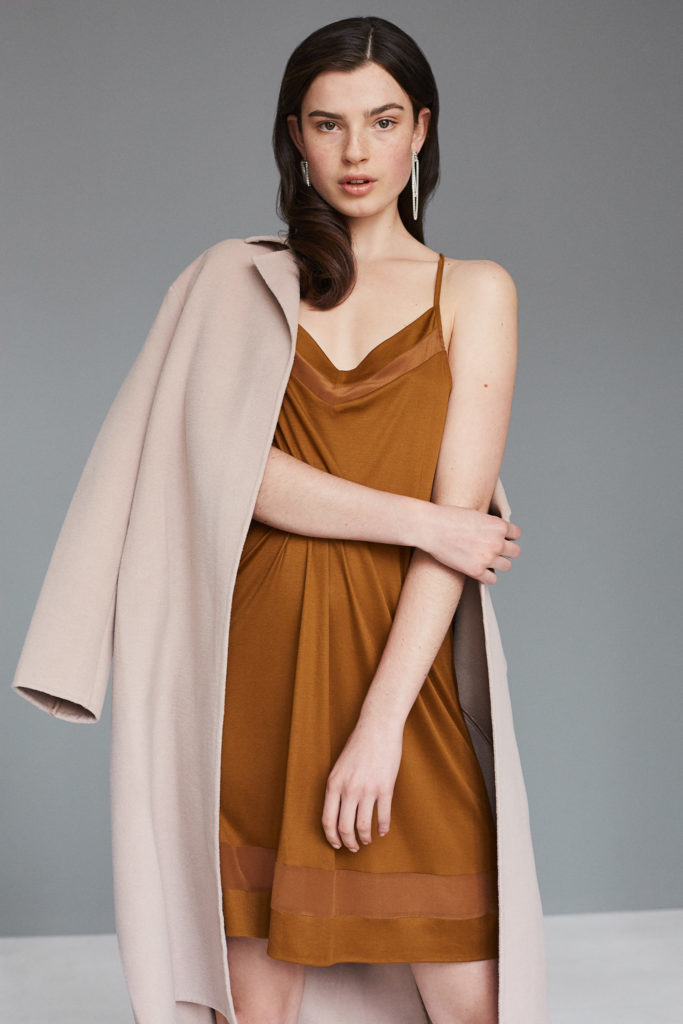 model-mit-mantel-ueber-schulter-und-kleid-im-studio