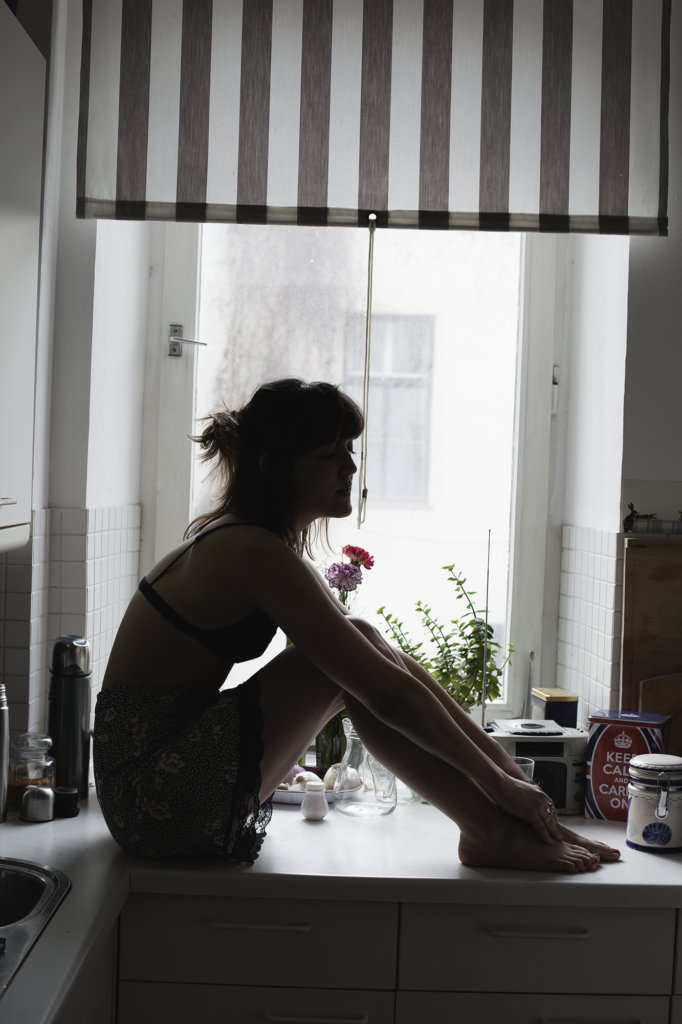 frau in küche, sitztauf der fensterbank, sehr stimmungsvoll