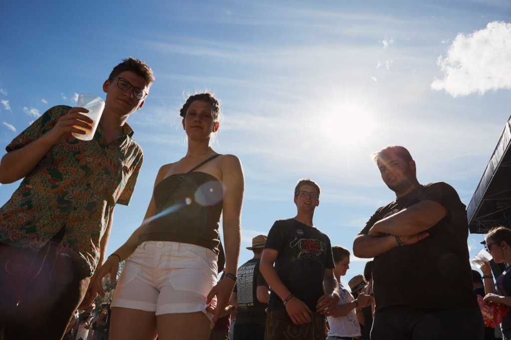gruppe von leuten vor der bühne, gegen die sonne, schauen in kamera