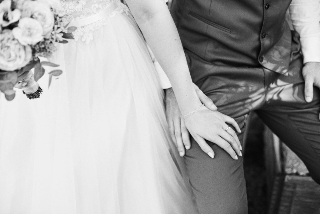 schwarz weiß foto von brautpaar, nur hände und unterkörper zu sehen