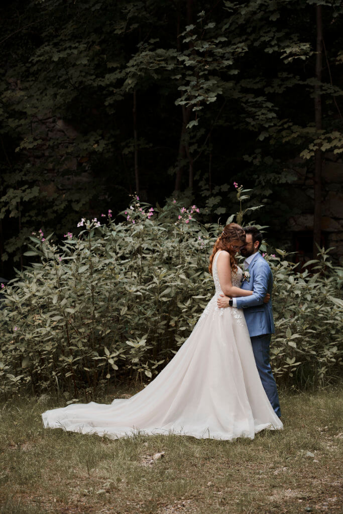 Brautpaar vor dunkler Kulisse, lange schleppe von Braut