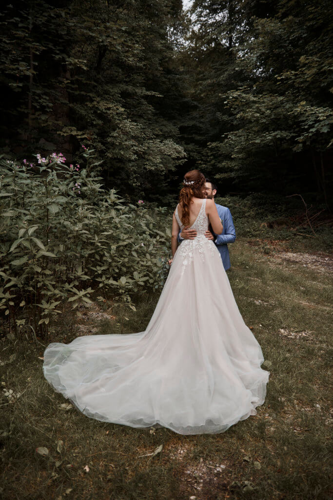 Brautpaar vor dunklem Wald, schauen sich an, schickes, langes Kleid