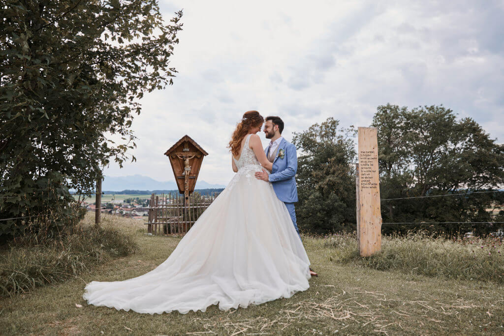 brautpaar schaut sich in die augen, auf wiese stehend, schicke kleidung