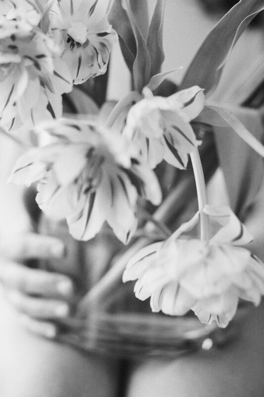 schwarz weiß foto von einer frau mit nackten beinen und einer blumenvase auf dem schoß