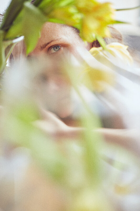 verzerrtes portrait von einer frau durch ein glas und blumen. künstlerische fotografie