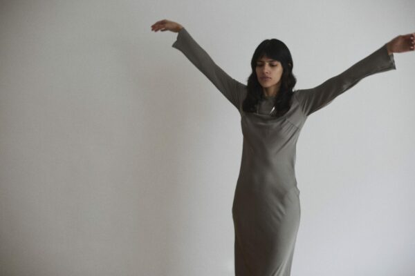 junges weibliches model in einem silbernen kleid mit erhobenen Armen.