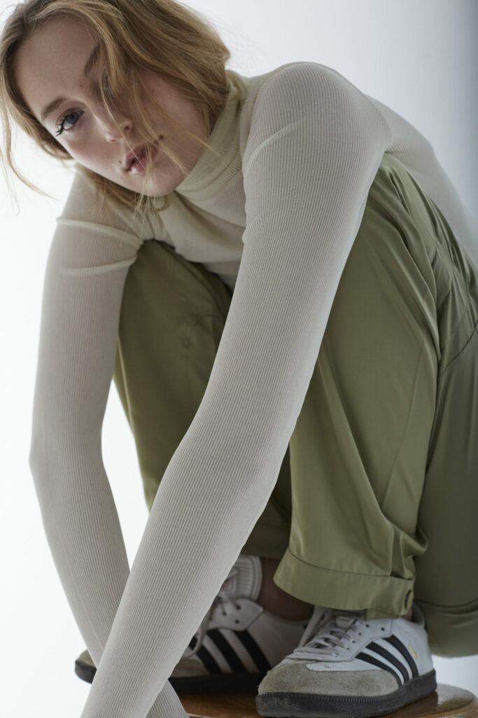 Weibliches Model sitzt auf einem Hocker und schaut in die Kamera.