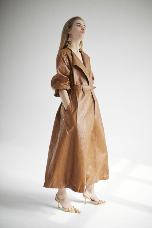 Weibliches Model in langem Ledermantel im Fotostudio.
