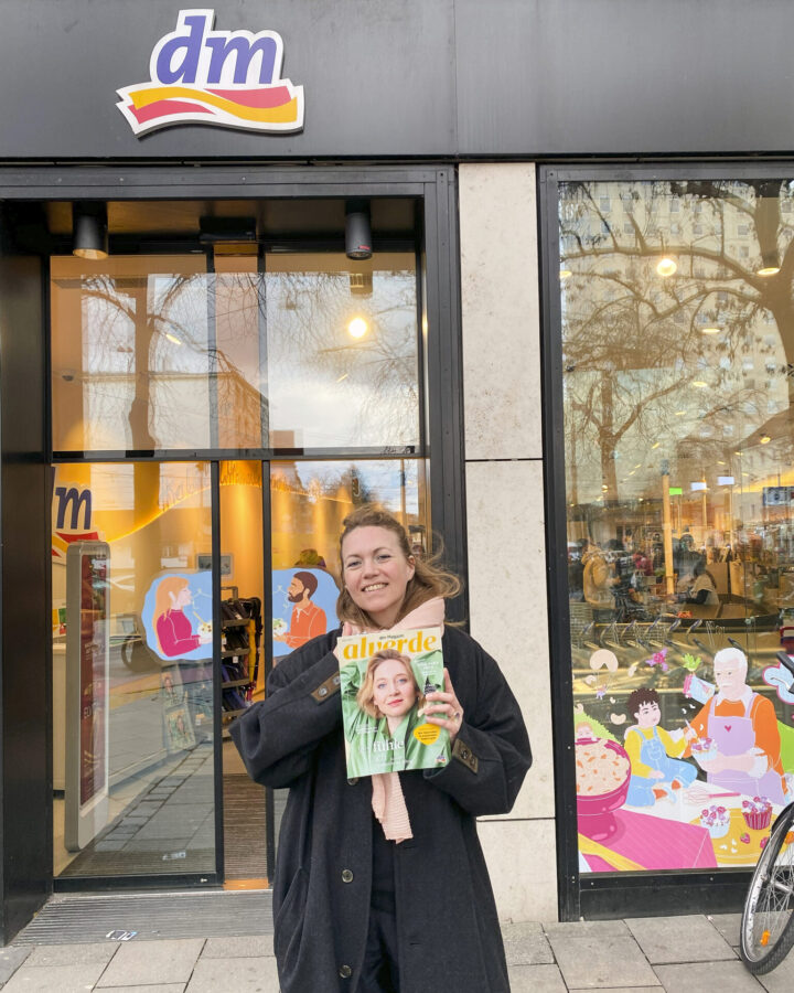 verena vötter, fotografin aus münchen steht mit dem alverde magazin lachend vor einem drogerie markt.