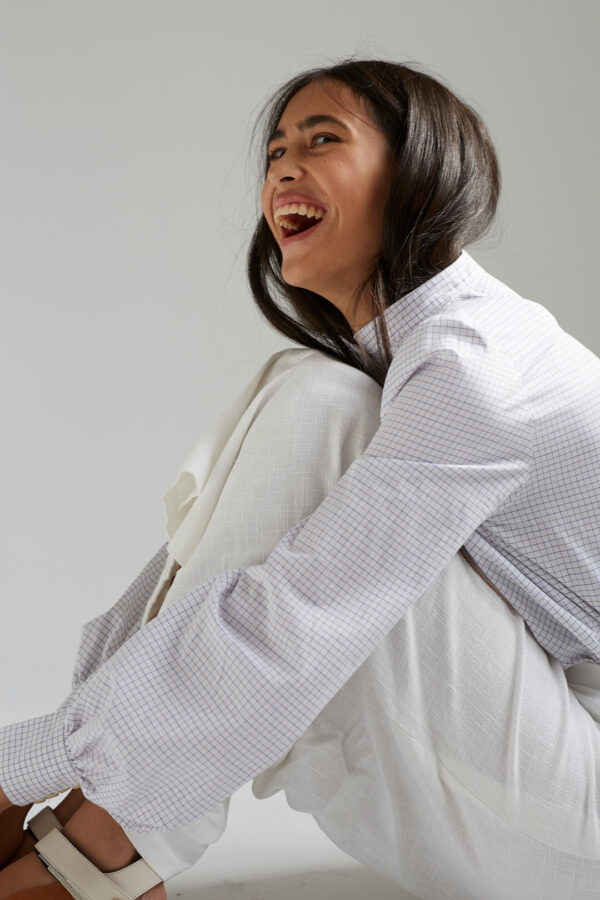 Weibliches Model im Fotostudio, sitzt am Boden und lacht.