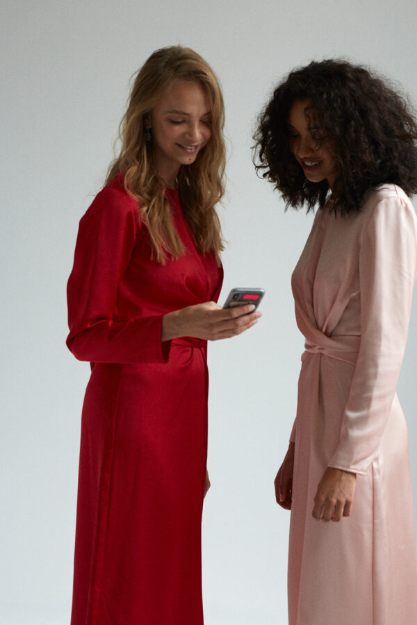 Zwei Models im Studio, das eine Model zeigt dem anderen etwas auf dem Handy.