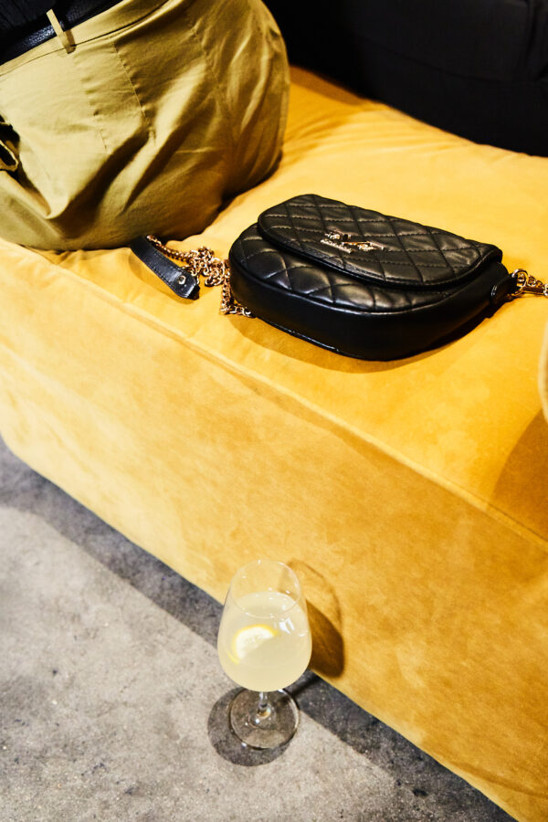 Eine gelbe Couch, eine Luxustasche und ein Drink. abstrakt fotografiert.
