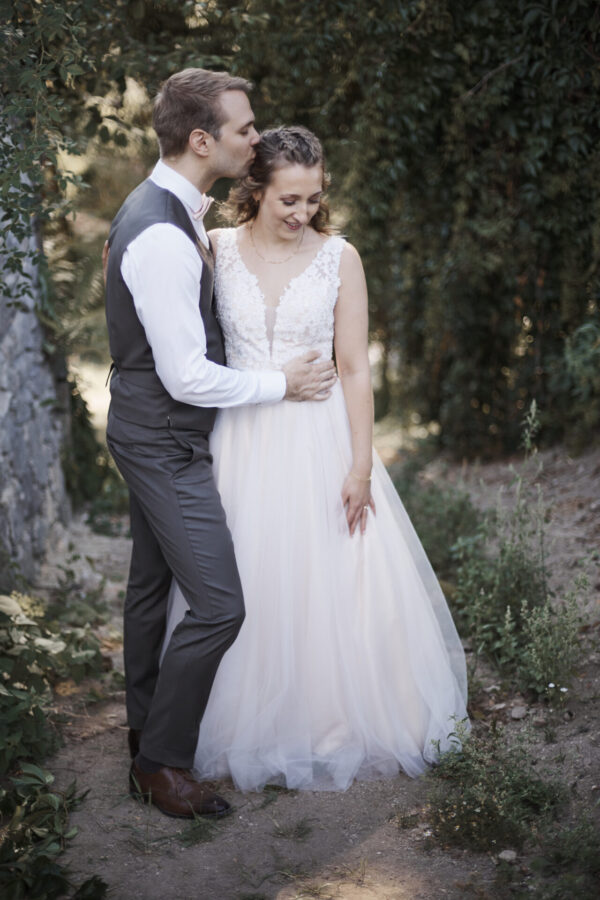 Ein hübsches junges Hochzeitspaar steht vor der Burg im Grünen zum Paarshooting.