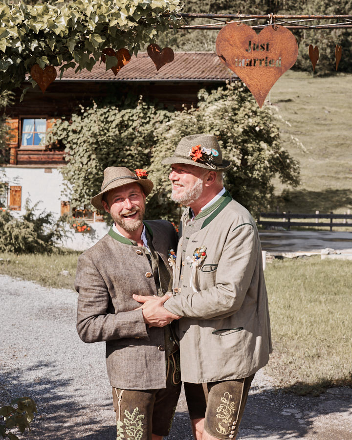 Schwules Hochzeitspaar in Tracht, fotografiert von Verena Vötter in München. Sie lachen und umarmen sich.