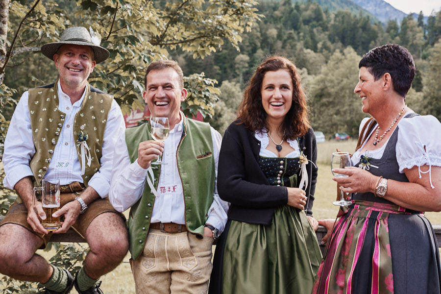 Eine Gruppe lachender Menschen in Tracht auf einer schwulen Hochzeit.