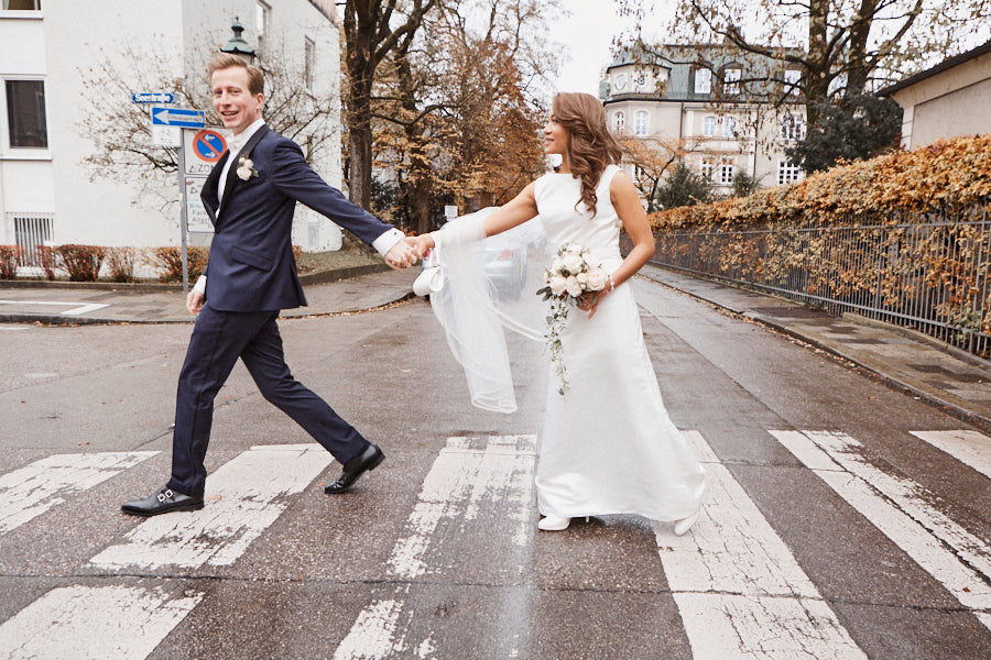 Der Bräutigam zieht die Braut über den Zebrastreifen.