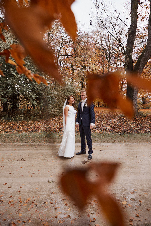 Ein brautpaar durch goldenes Laub fotografiert.