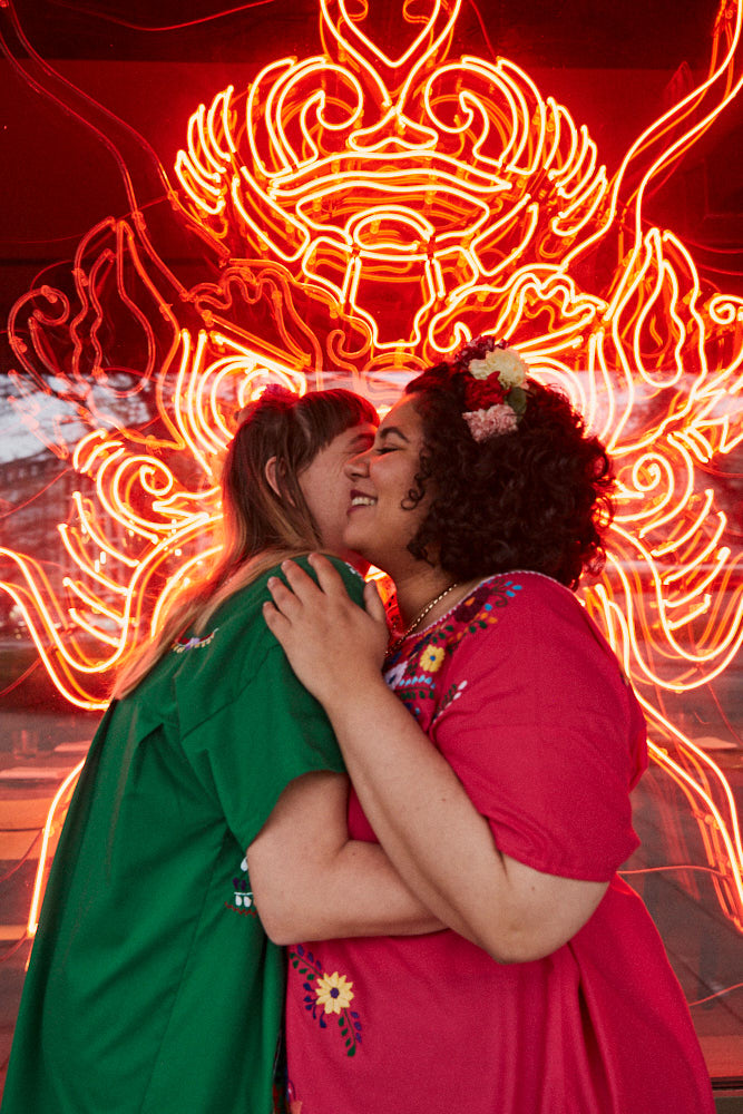 Zwei Bräute, die sich in München vor einem Restaurant umarmen.