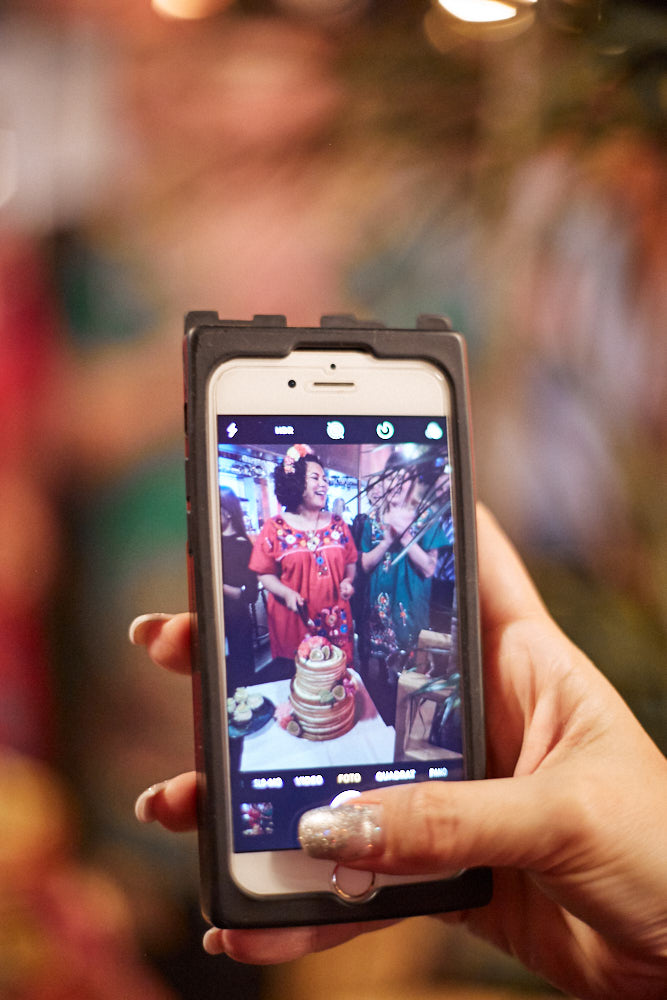 Ein Foto von einem Handyfoto mit dem lesbischen Brautpaar beim Kuchenschneiden.