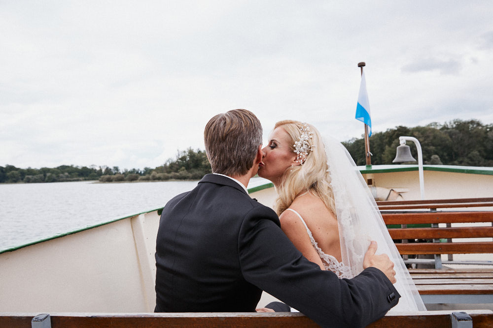 Braut küsst Bräutigam auf die Backe auf einem Schiff auf dem Chiemsee.